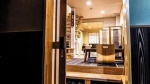 An interior with a wooden reception desk, a seating area, and a view through a doorway.