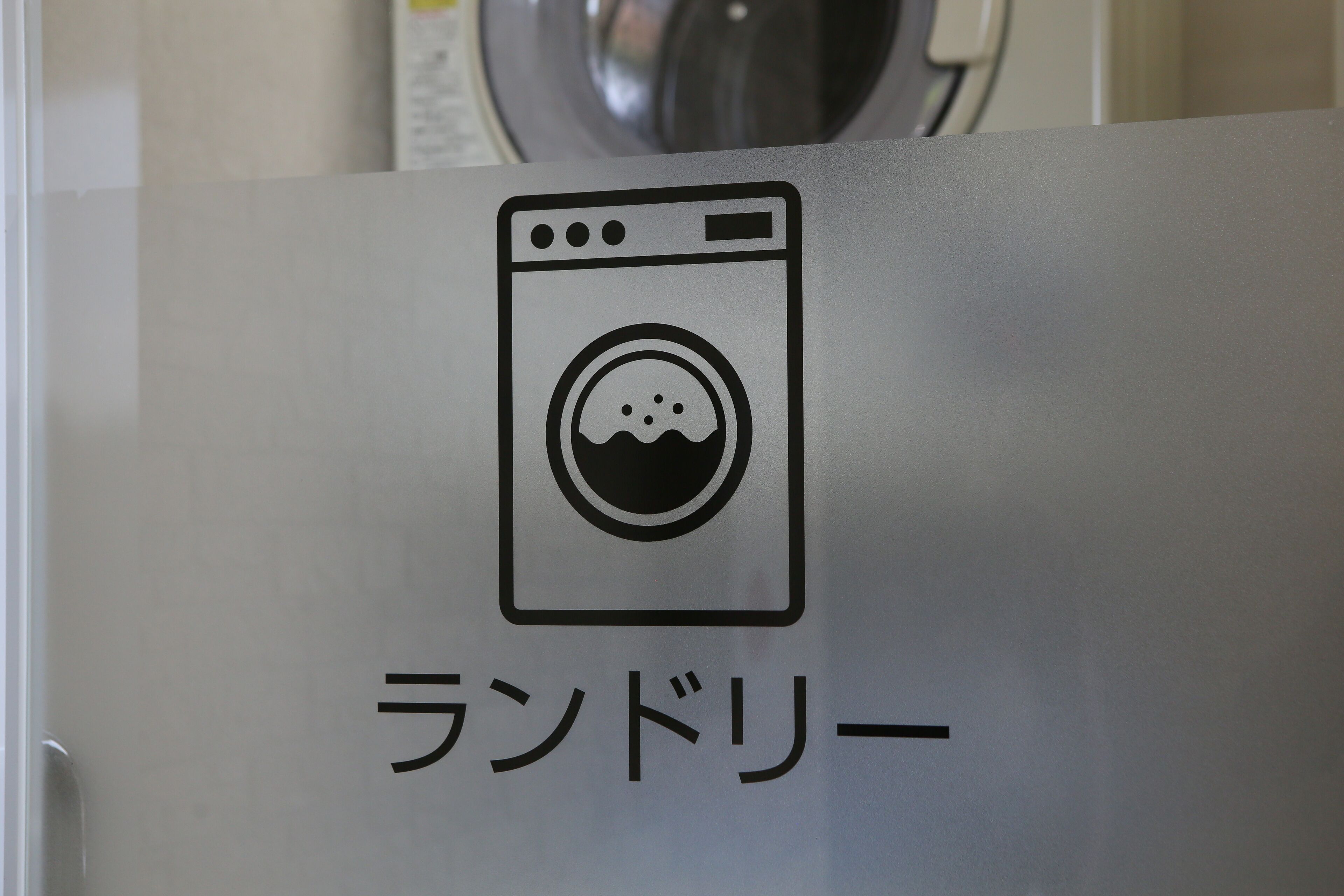 A sign with a washing machine icon and Japanese text.