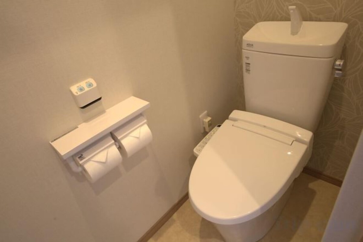 A toilet with a paper towel dispenser and a flush button.