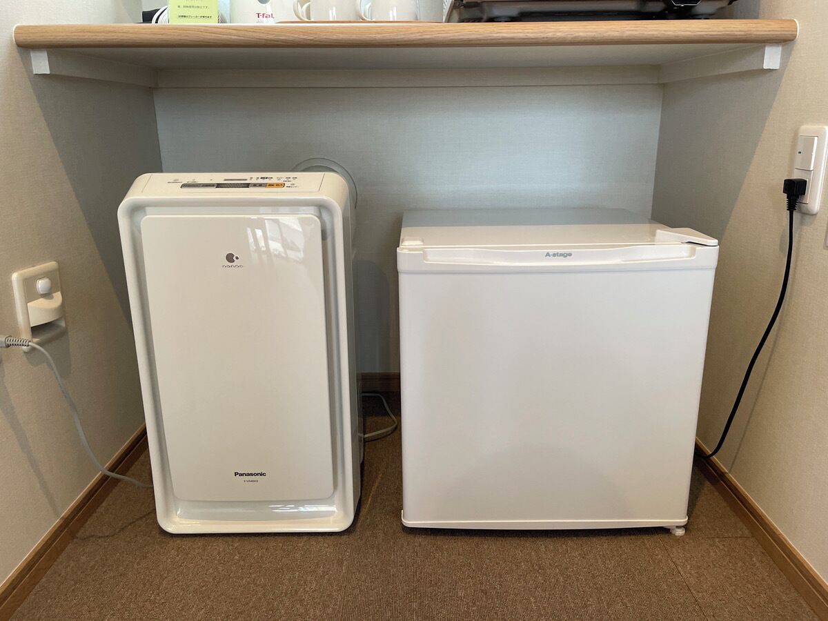 Dos refrigeradores blancos, uno con compartimento congelador, y un enchufe en la pared.