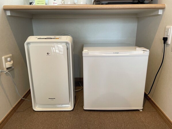 Deux réfrigérateurs blancs, dont l’un est doté d’un compartiment congélateur, et une prise de courant sur le mur.