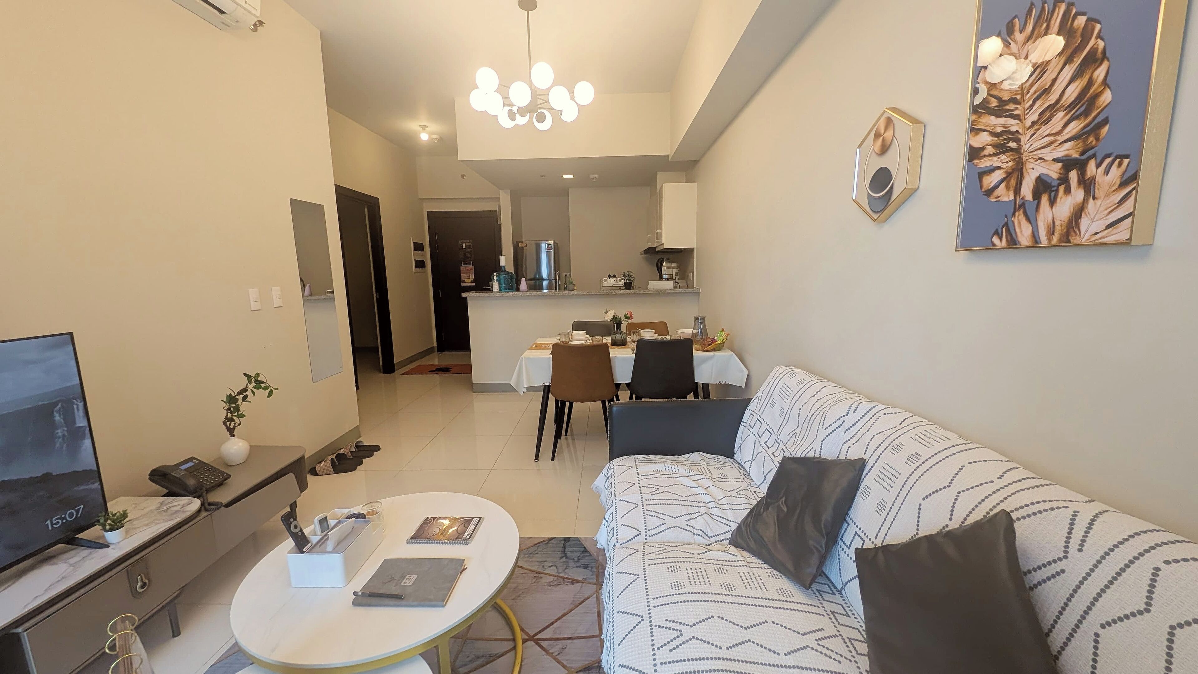 A modern living room with a sofa, coffee table, TV, and a dining area with chairs and a table.