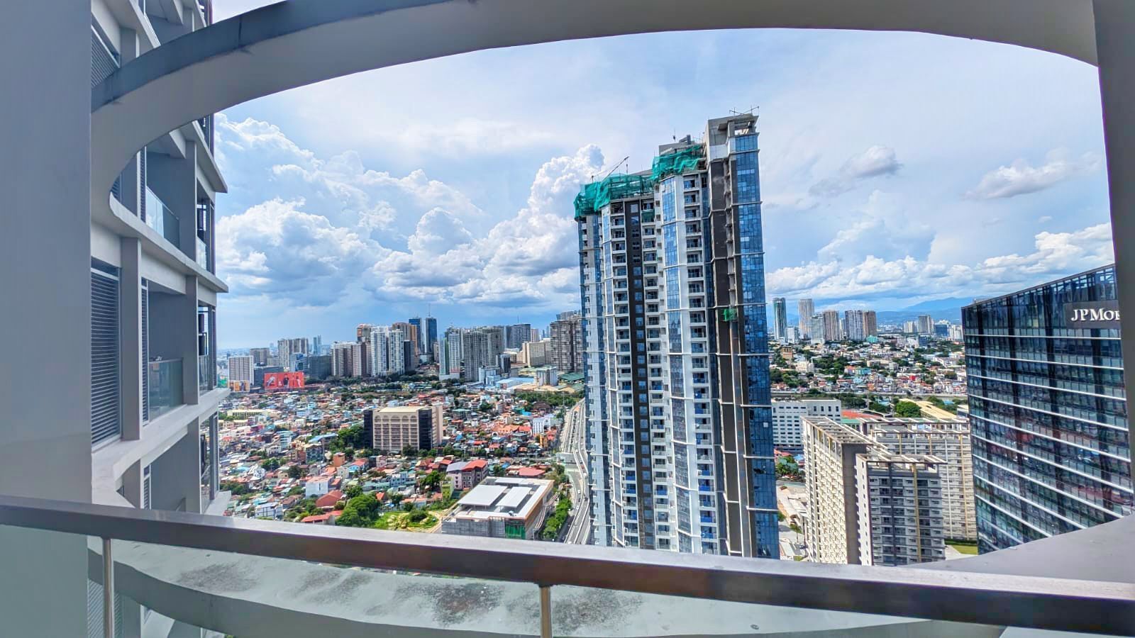 Un edificio alto de diseño moderno, rodeado de una zona urbana densa con otros edificios de gran altura.