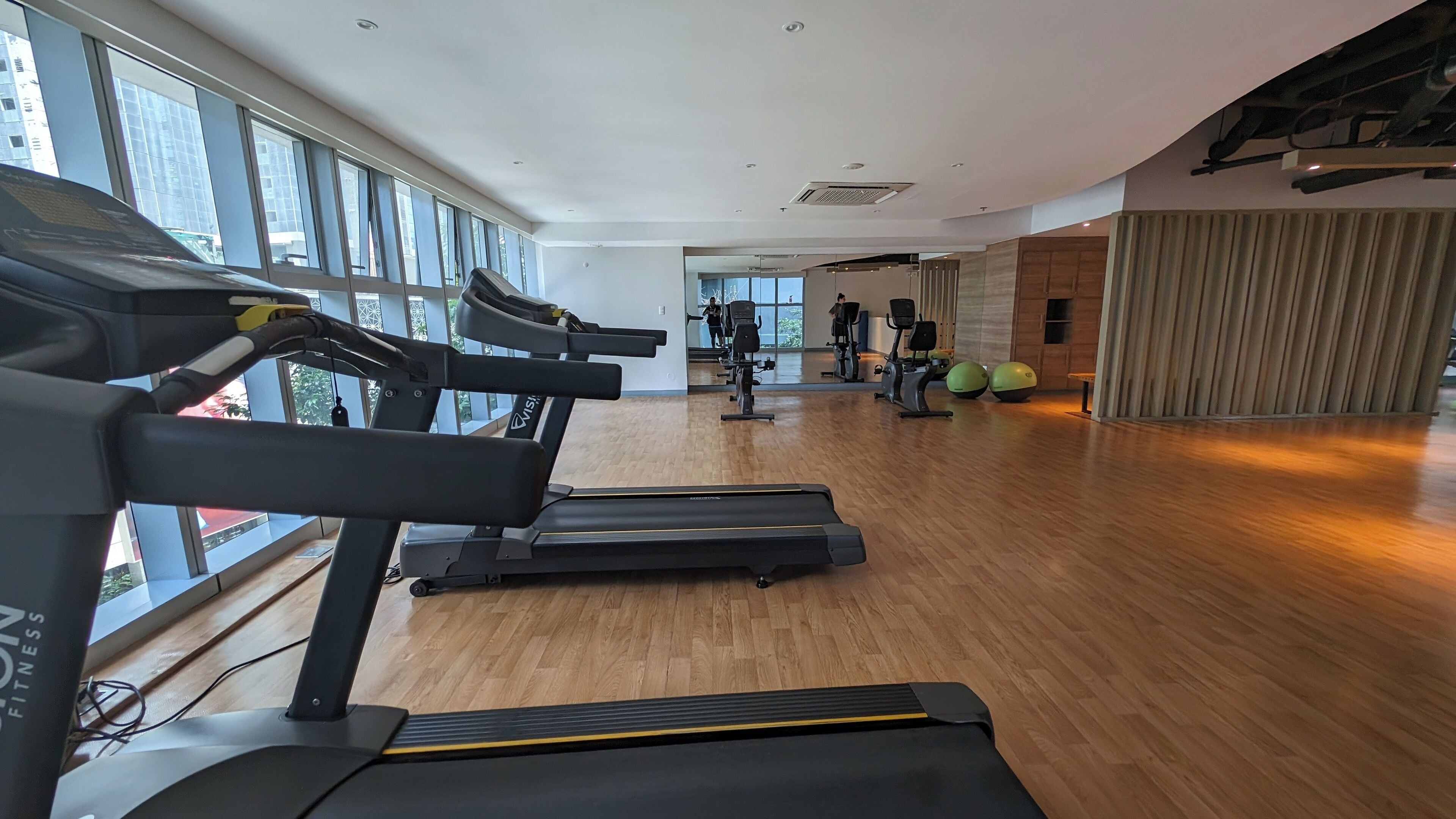 Un gimnasio con cintas de correr, bicicletas estáticas y pesas.