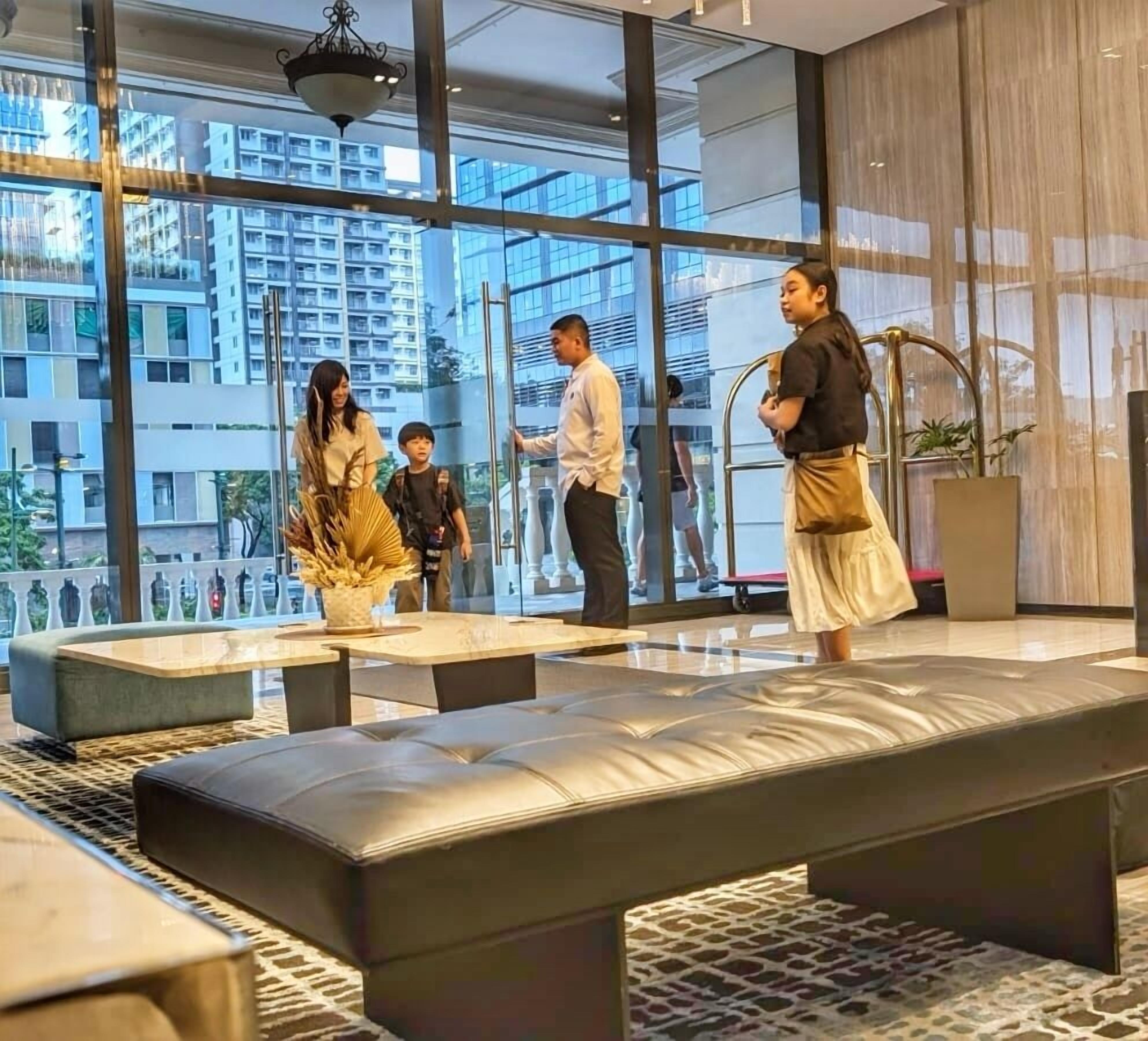 Un hall d’hôtel moderne, doté de grandes fenêtres, d’un espace salon et offrant une vue sur le paysage urbain.