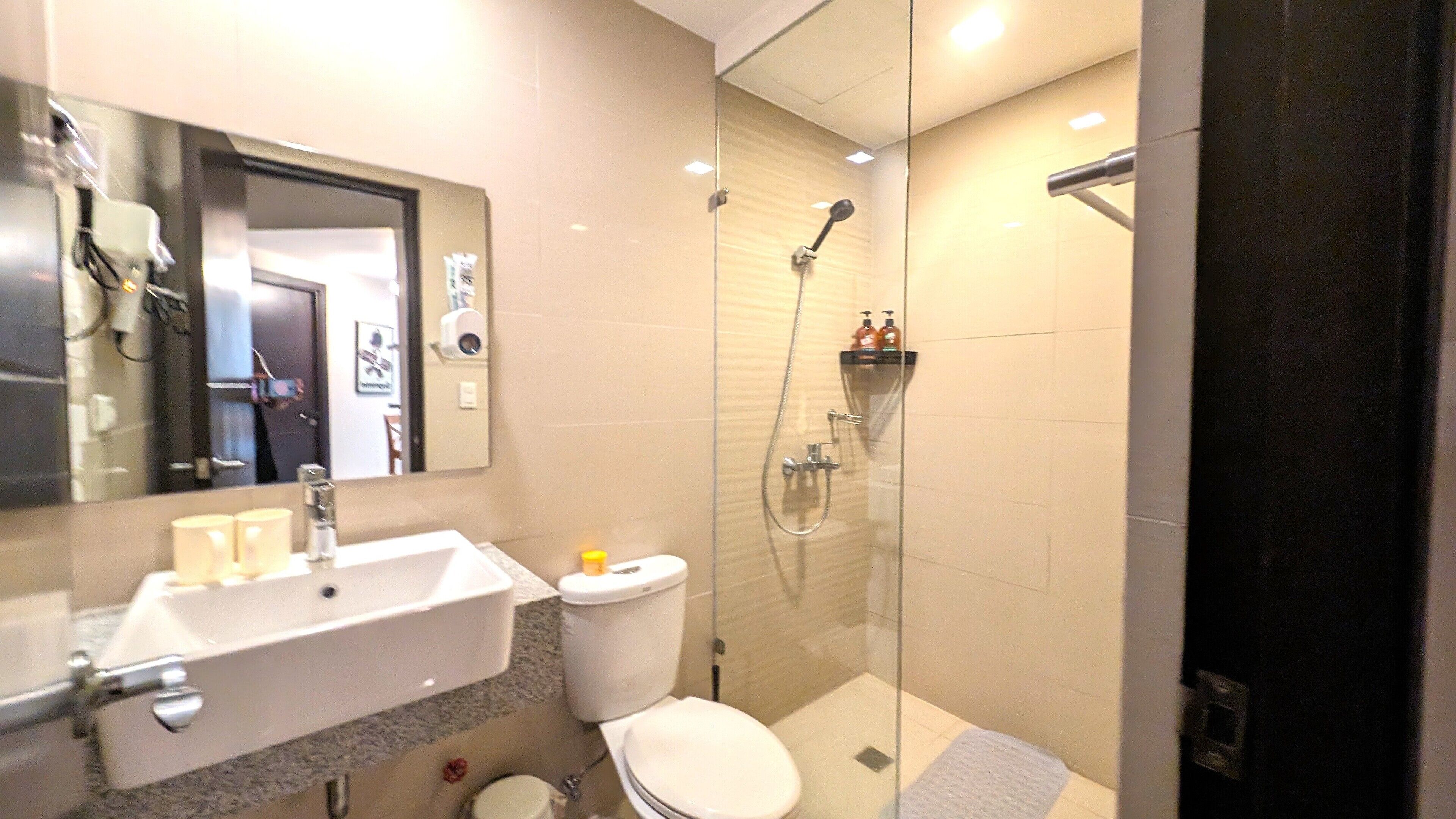 A modern bathroom with a glass-enclosed shower, a white sink, and a toilet.