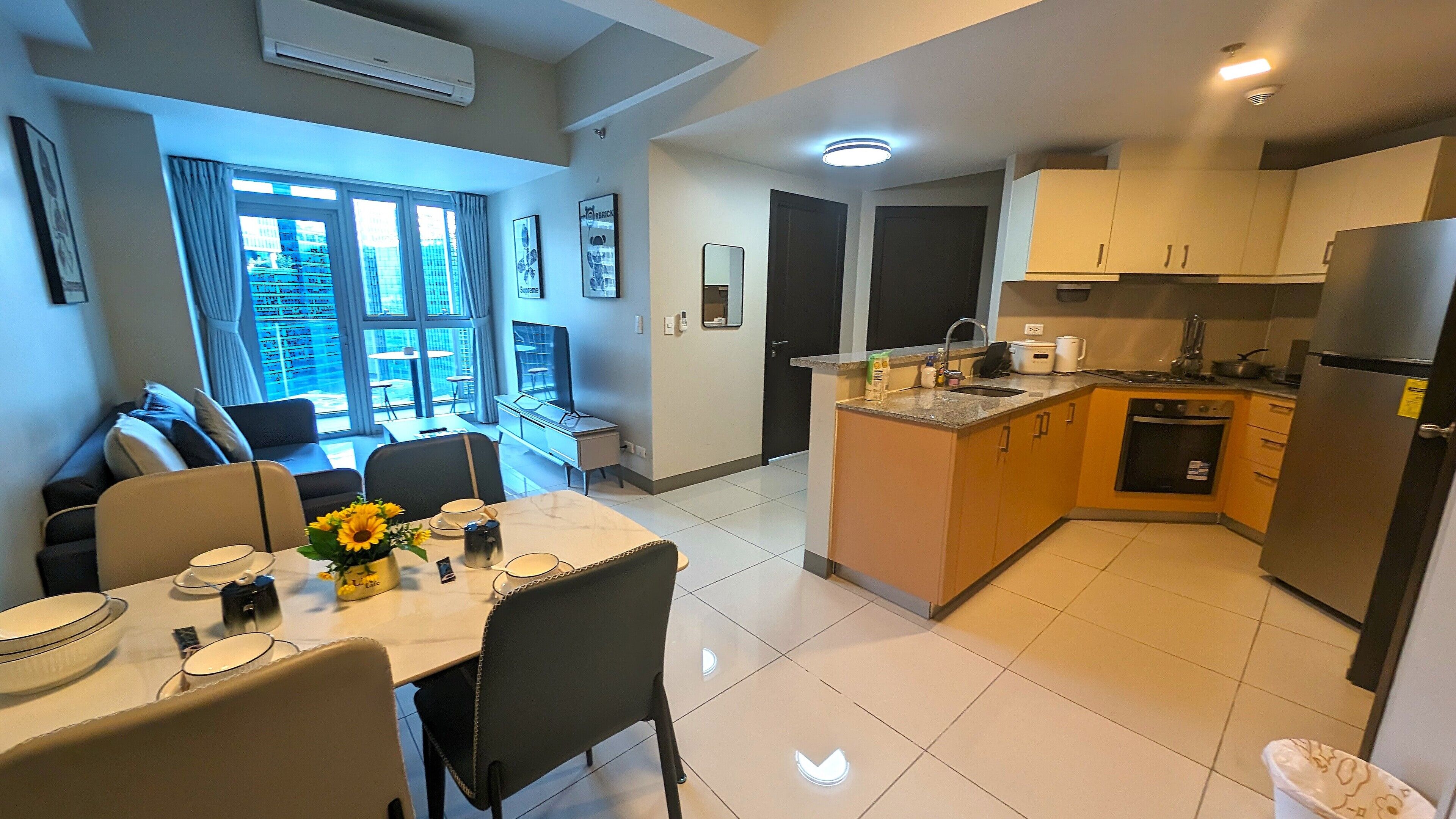 A modern apartment with a dining area, kitchen, and a balcony with a city view.