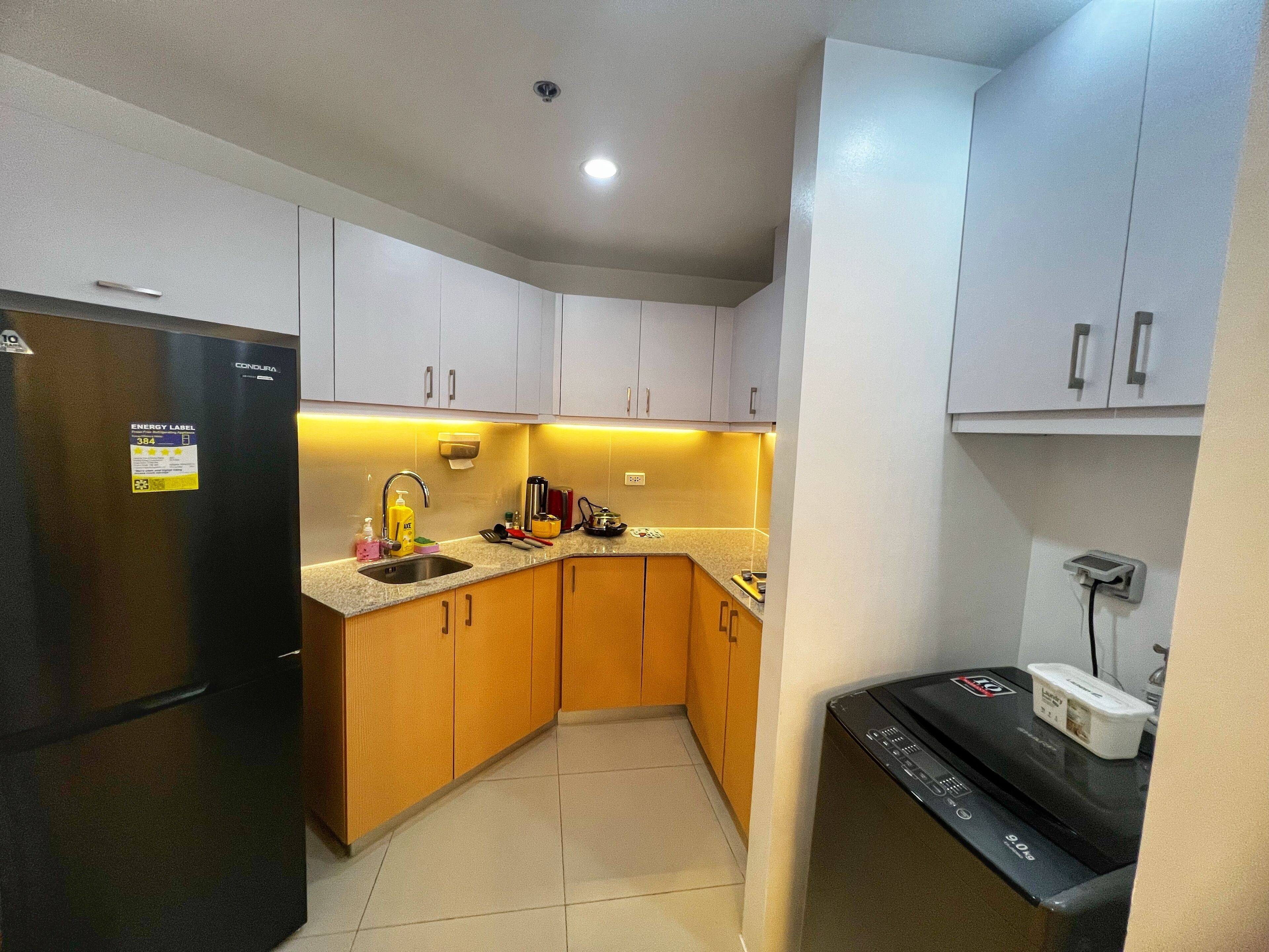 A compact kitchen with a refrigerator, sink, and dishwasher.