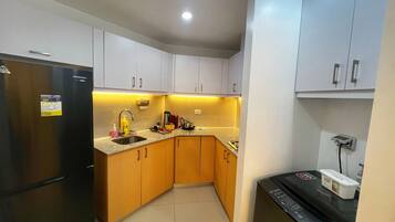 A compact kitchen with a refrigerator, sink, and dishwasher.