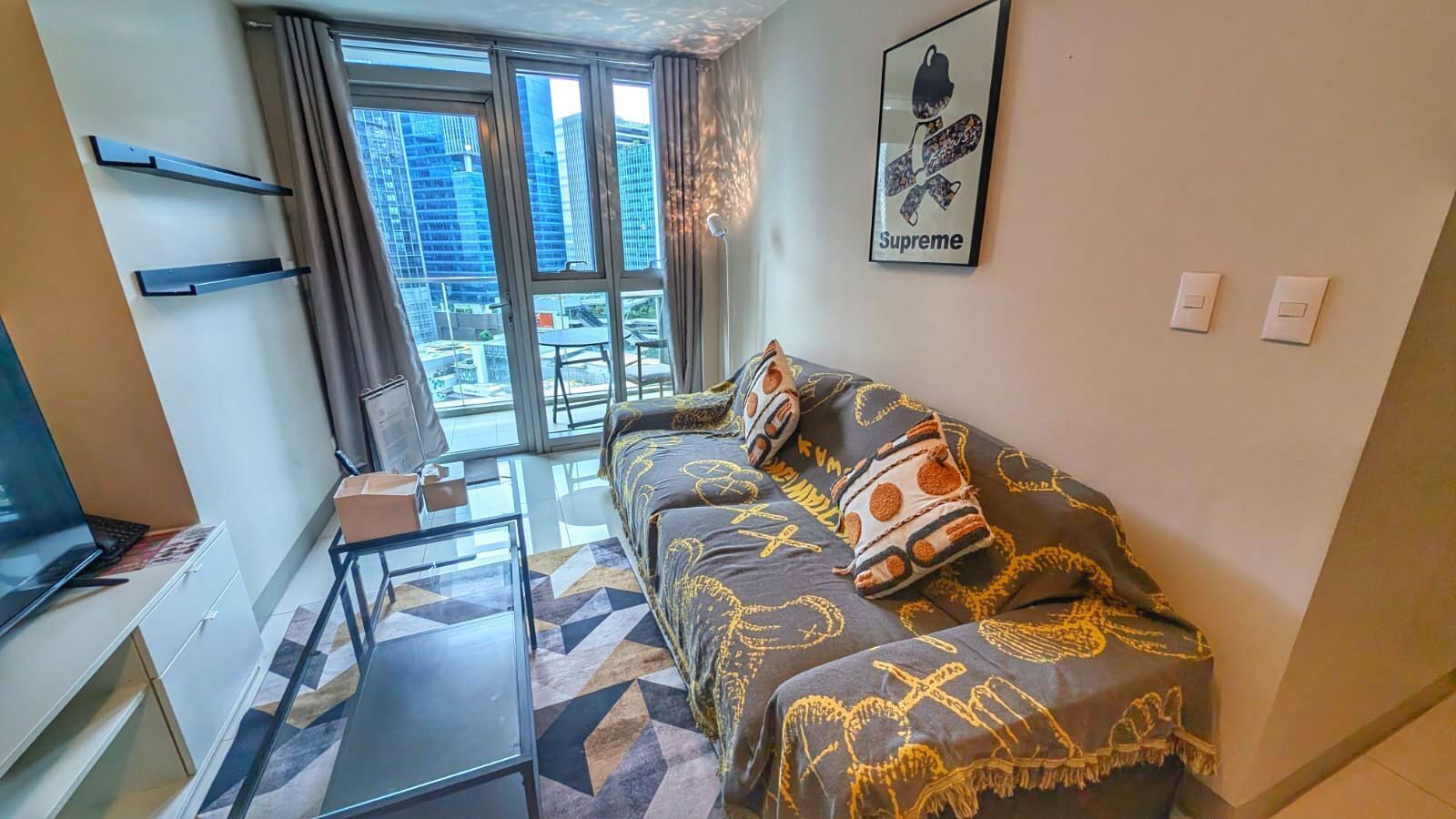 Quarto de hotel moderno com uma cama grande, uma mesa de trabalho e vista para a cidade através de janelas amplas.