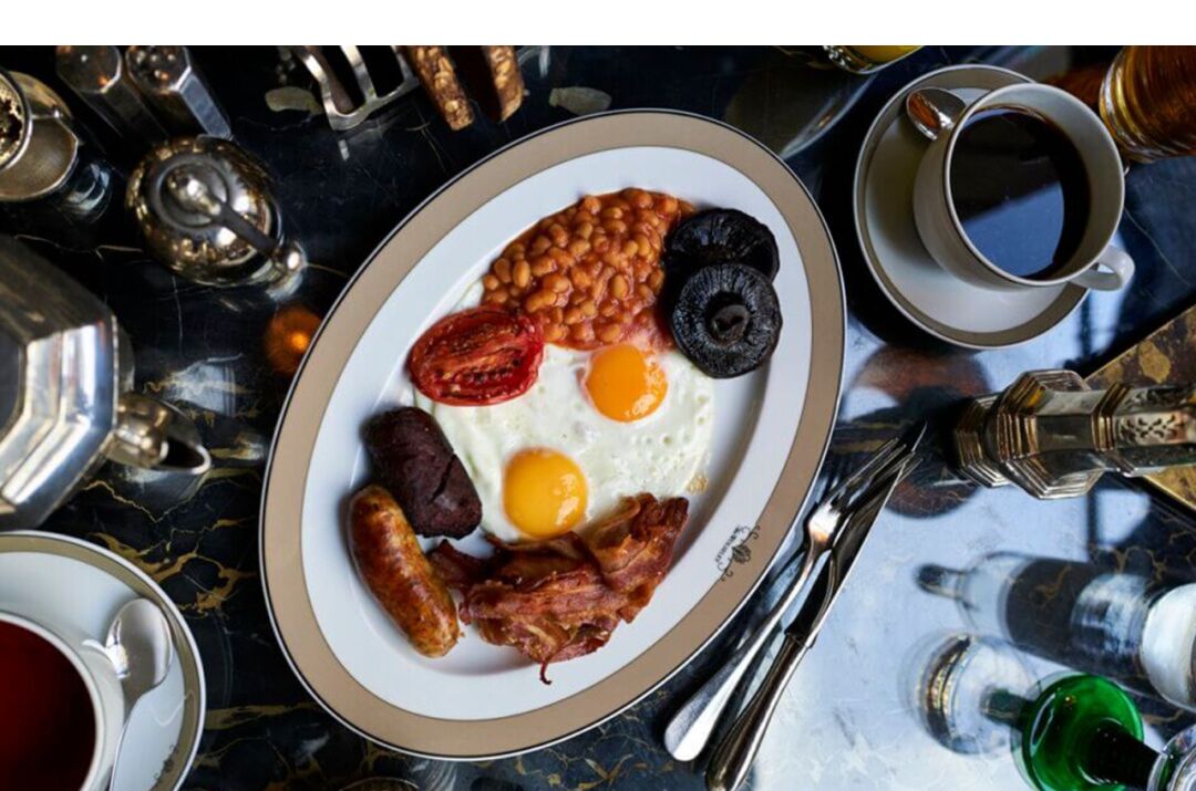 Un plato de desayuno con huevos, frijoles, tomates y salchichas.