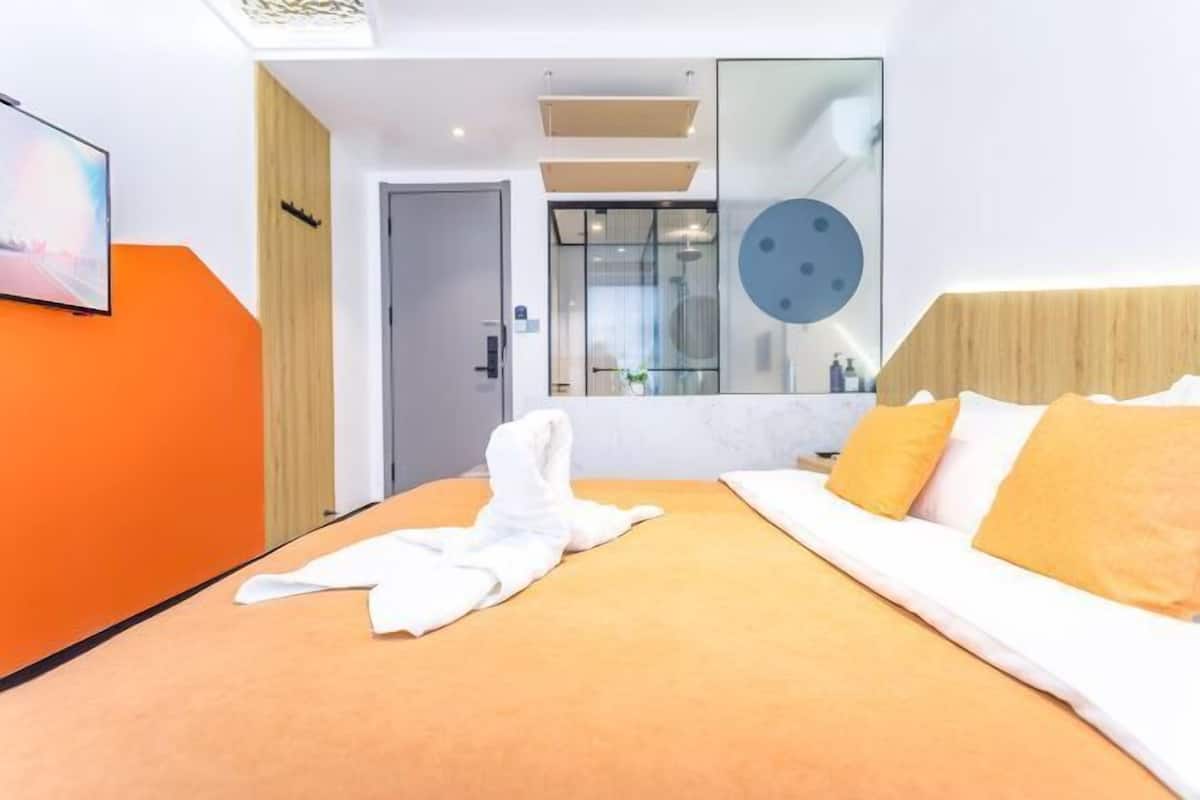 A hotel room with a bed, a shower area, and a large mirror.