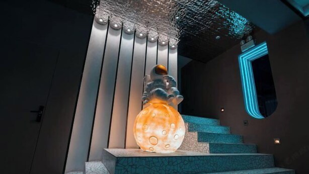 Un escalier surmonté d’une sculpture unique, illuminée.