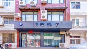 Un bâtiment doté de plusieurs unités de climatisation, une devanture de magasin avec une enseigne et un escalier menant à l’entrée.