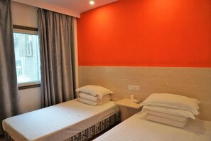 A small hotel room with two single beds, a window with curtains, and a wall painted in a warm orange color. - Shipu Xinxing Hotel (Xiangshan)