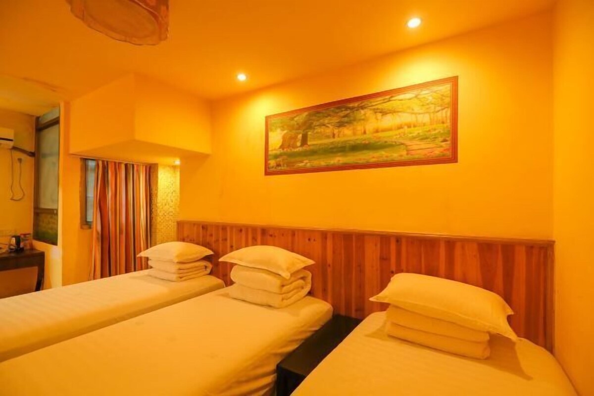 A room with two beds, a wooden headboard, a painting, and a window with curtains.