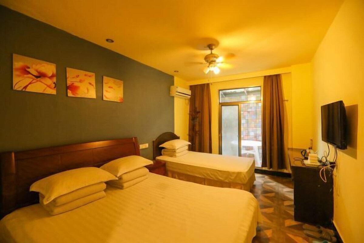A hotel room with a bed, a desk, a ceiling fan, and a window with curtains.