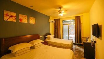 A hotel room with a bed, a desk, a ceiling fan, and a window with curtains.