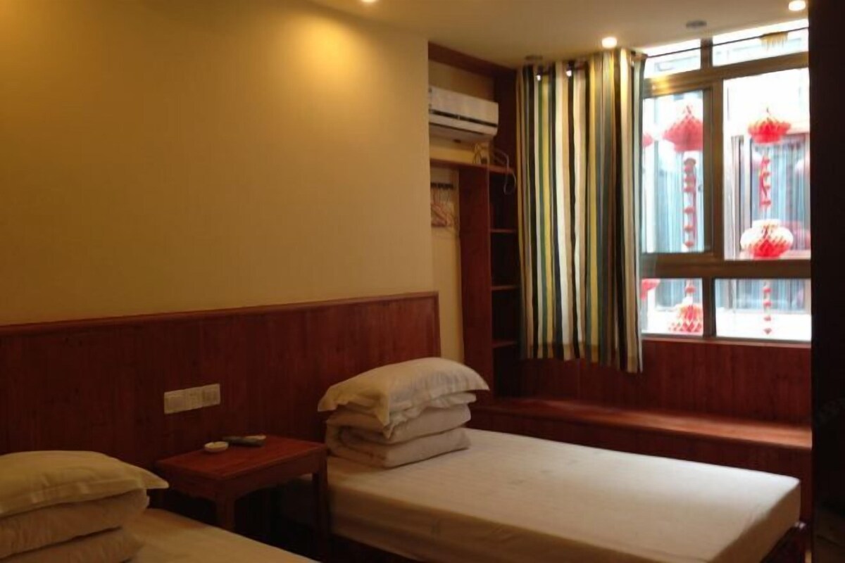 A hotel room with a single bed, a bedside table, a wardrobe, and a window with curtains.