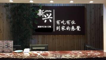 A reception desk with a digital display, a plant, and a marble counter.