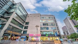 Een modern stadsgebouw met meerdere commerciële etalages op de begane grond.