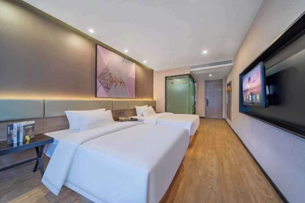 Une chambre d’hôtel avec deux lits, une télévision et un tableau au mur.