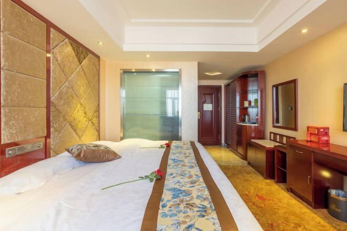 A hotel room with a bed, a desk, a television, and a bathroom.