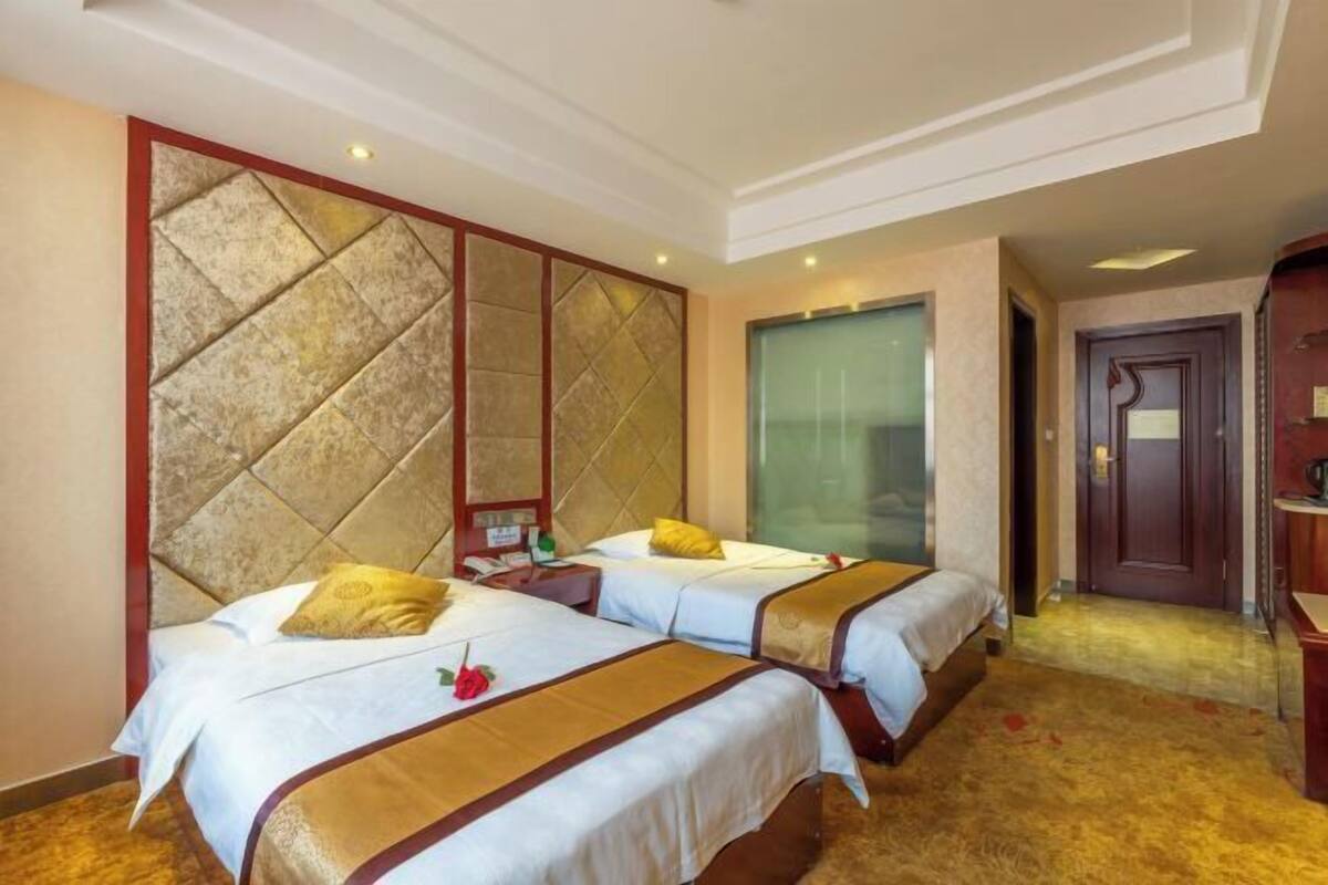 A hotel room with two beds, a large wall panel, a wooden door, and a carpeted floor.