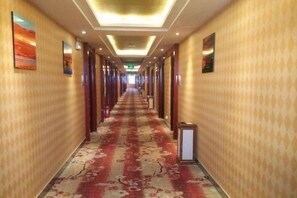 A hotel corridor with a patterned carpet, doors on both sides, and artwork on the walls. - Jintaolai Hotel (Ejin Banner)