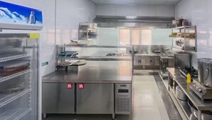 A commercial kitchen with stainless steel appliances, a large refrigerator, and a display case. - Jintaolai Hotel (Ejin Banner)