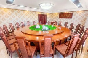 Un salón de conferencias con una mesa redonda, sillas y un centro de mesa decorativo.