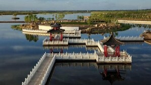 A serene water body with traditional Chinese-style pavilions and a white fence. - Jintaolai Hotel (Ejin Banner)