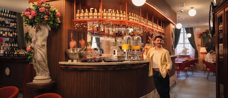 A bar area with a marble counter, bottles, glasses, and a statue.