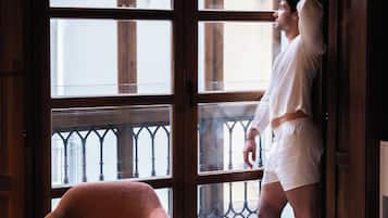 Una persona de pie junto a una ventana con vista a un balcón y barandilla.