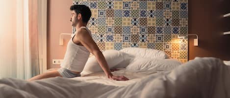 A person sitting on a bed with a patterned wall behind them.