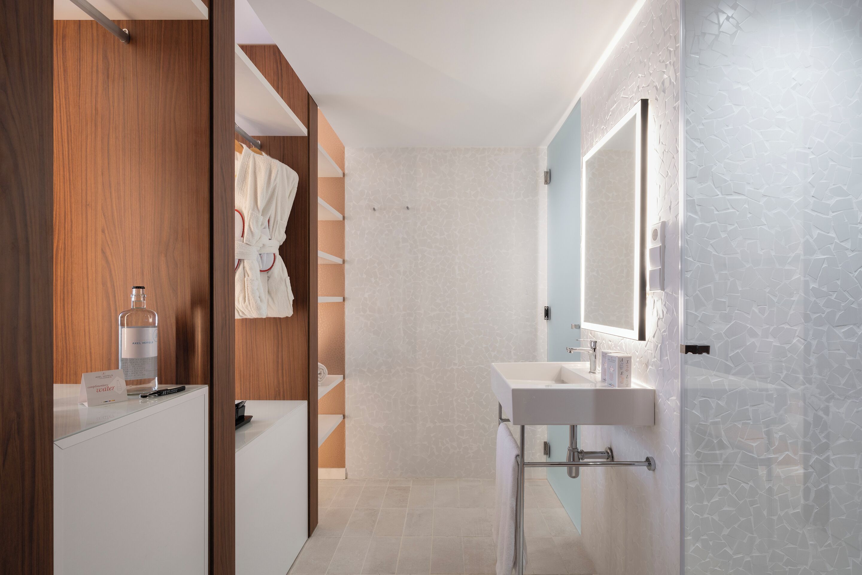 Un baño moderno con tocador de madera, cabina de ducha con vidrio y un espejo grande.