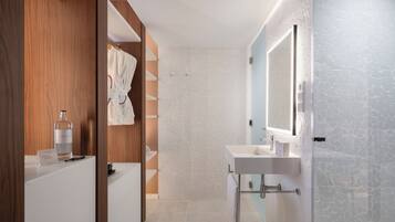 Un baño moderno con tocador de madera, cabina de ducha con vidrio y un espejo grande.