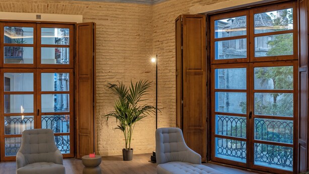 A room with a high ceiling featuring intricate frescoes, large windows with wooden shutters, and a potted plant. - Axel Hotel Valencia – Adults Only (Valencia)