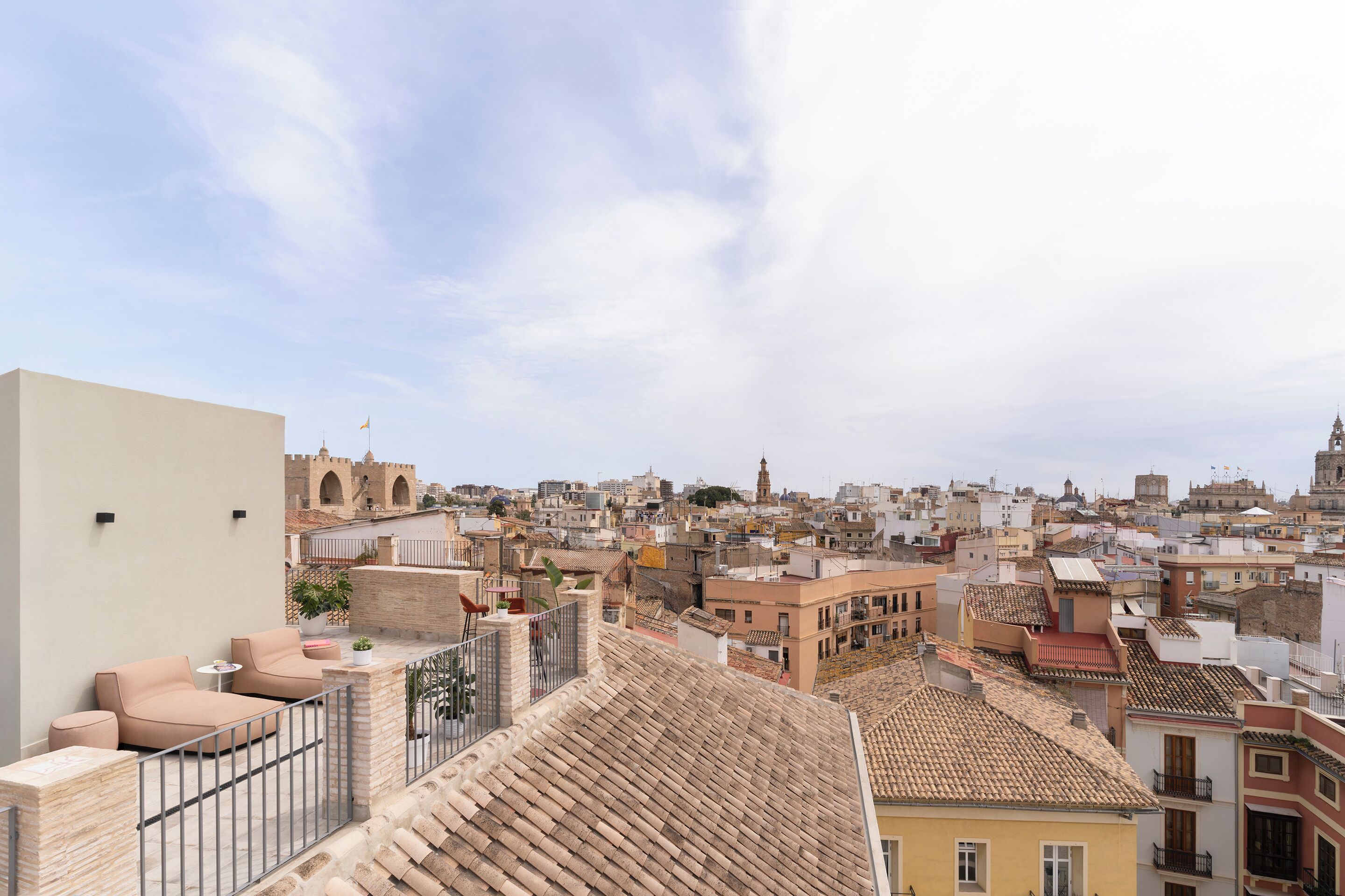 Una terraza en la azotea con un sofá color crema, una mesita y una planta en maceta.