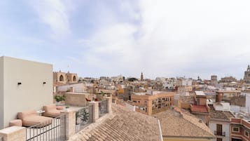 Una terraza en la azotea con un sofá color crema, una mesita y una planta en maceta.