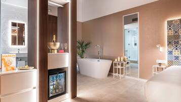 Un baño moderno con una bañera independiente, un tocador con espejo y un minibar.