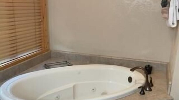 Ein Badezimmer mit einer freistehenden Badewanne, einem Handtuchhalter und einem Fenster mit Jalousien.