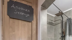 Una puerta de madera con un letrero que dice "Aloe Storage", un área de ducha con cortina blanca y una maceta con cañas altas.