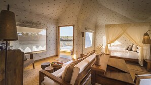 Une pièce confortable et bien éclairée, aménagée comme une tente, avec un grand lit, un coin salon et une vue sur la plage.