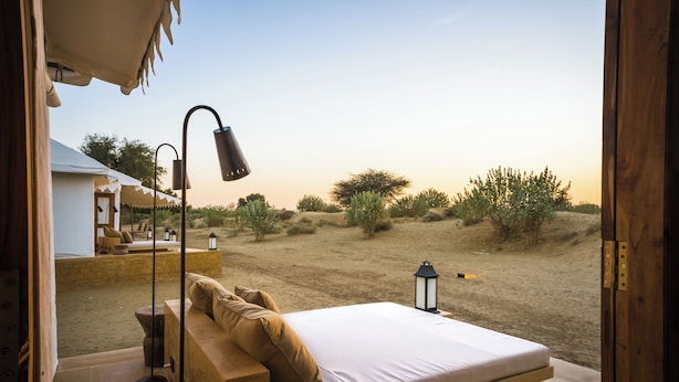 Une chambre à coucher avec un lit, une table de chevet, une lampe et une vue sur le paysage désertique.
