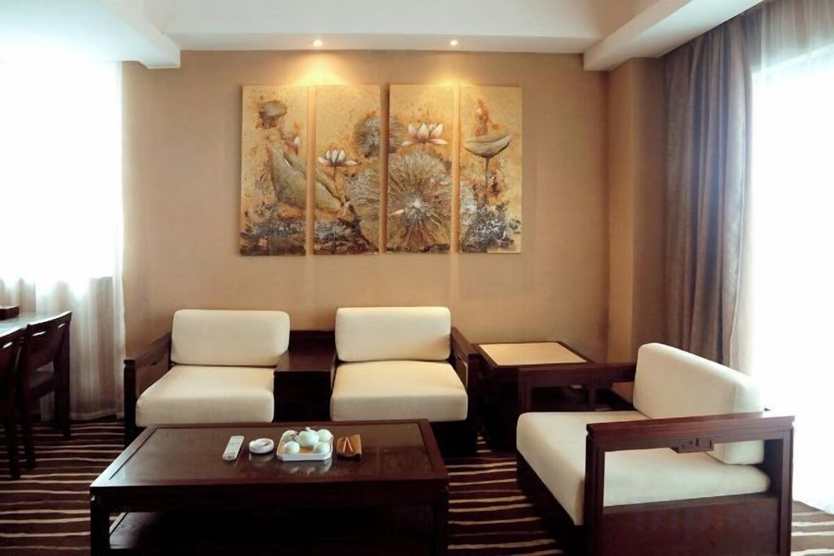 Une chambre d’hôtel dotée d’un coin salon, d’une table basse et d’un grand tableau mural.