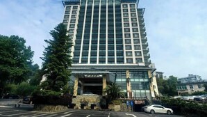 Een hoog, modern hotel met een glazen gevel, meerdere verdiepingen en een centrale ingang.