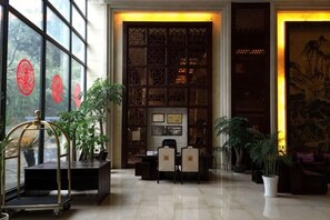 Un hall d’entrée avec un comptoir de réception, un espace salon et de grandes fenêtres ornées de décorations rondes rouges.
