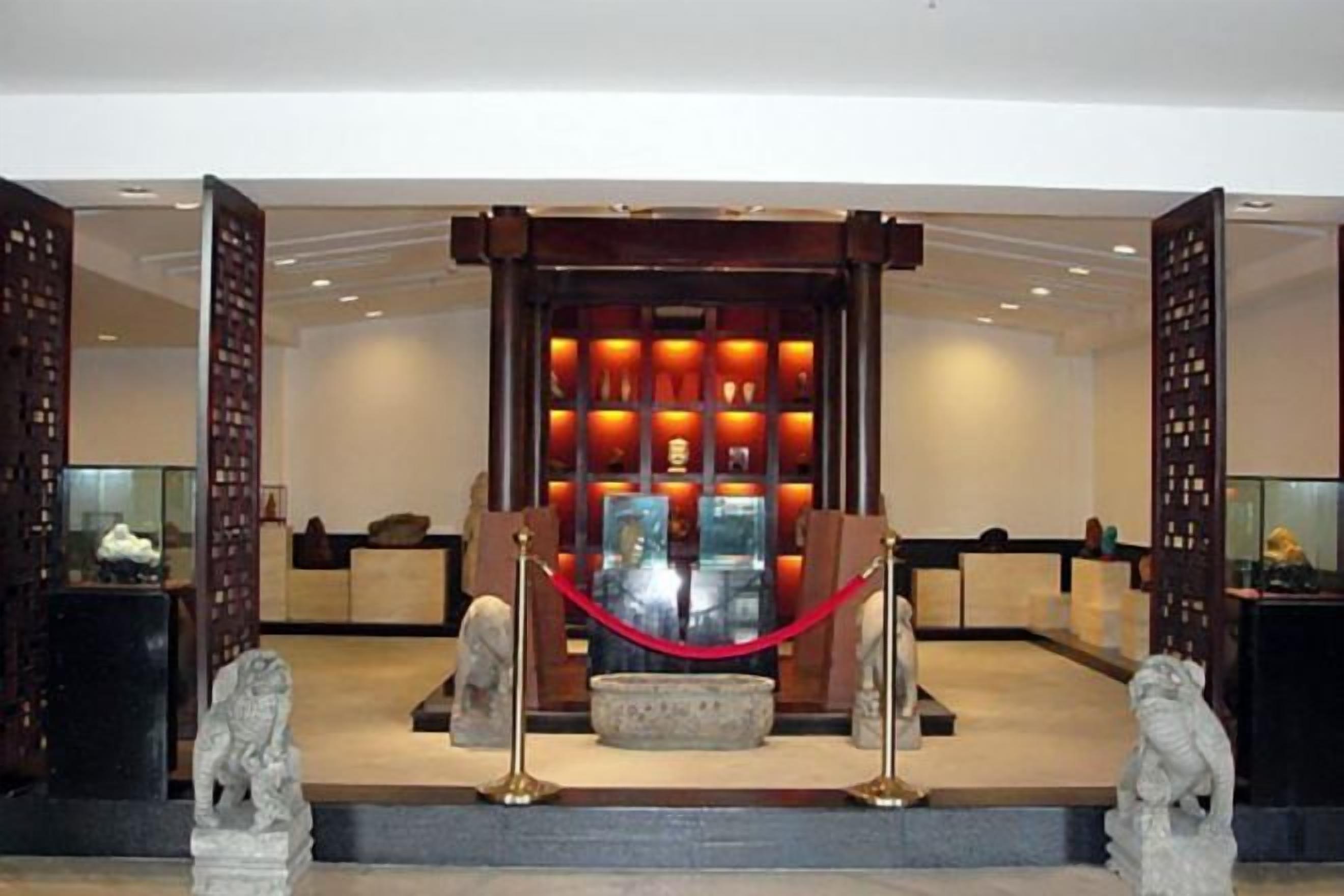 Ein Empfangsbereich mit einem traditionellen chinesischen Altar, einer roten Seilsperre und zwei steinernen Löwenstatuen.