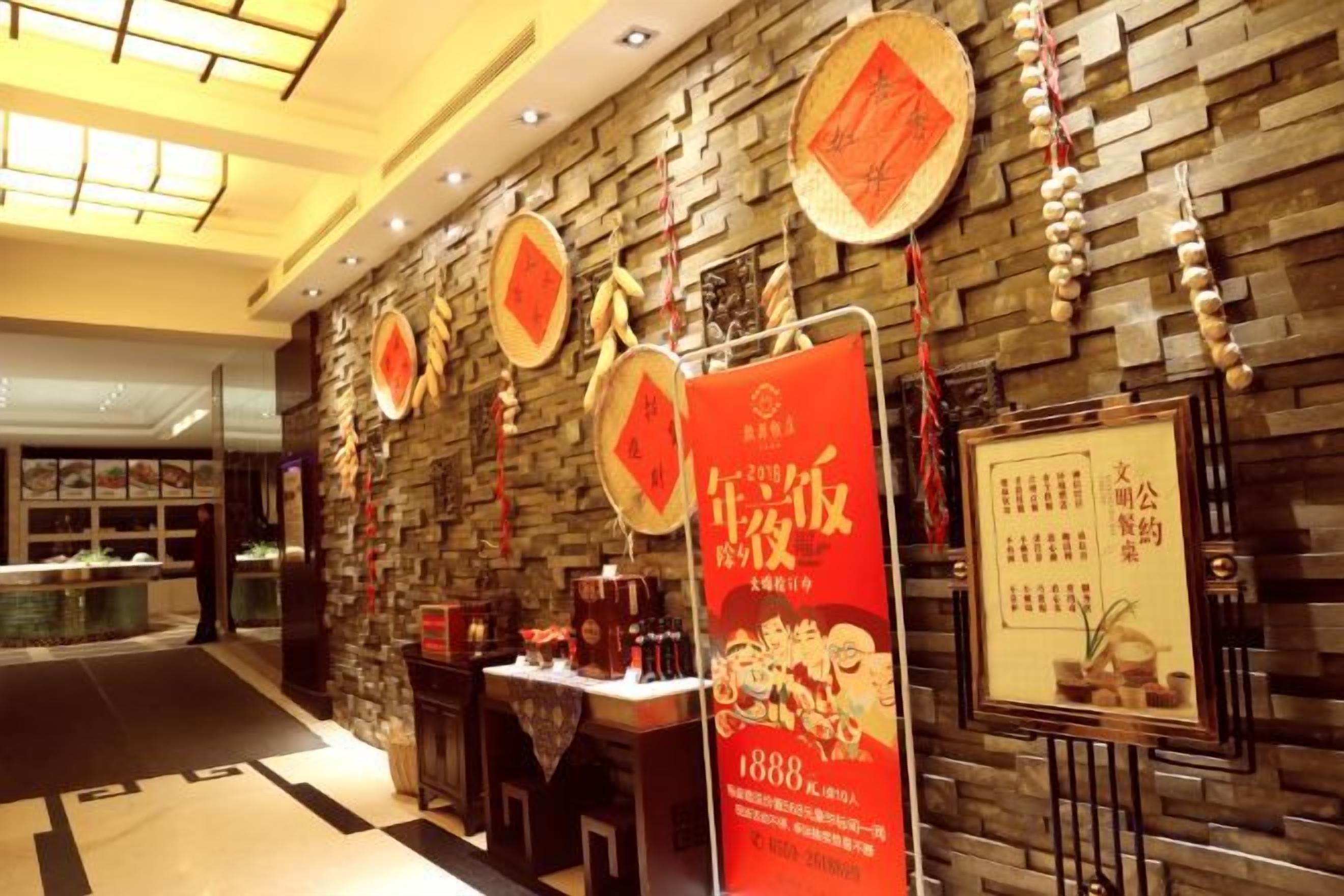 Vestíbulo de hotel con pared de piedra, detalles en rojo y una mesa de exhibición con objetos.